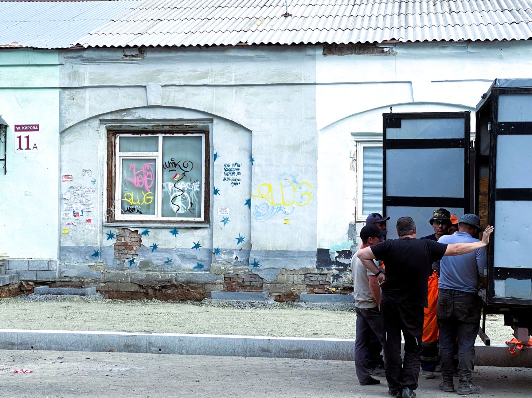 Workers in front of a building with a peace symbol in the window